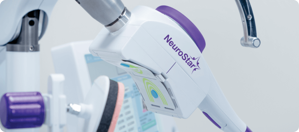 NeuroStar TMS therapy device with purple accents positioned near a patient's head, showing the magnetic coil and digital display screen
