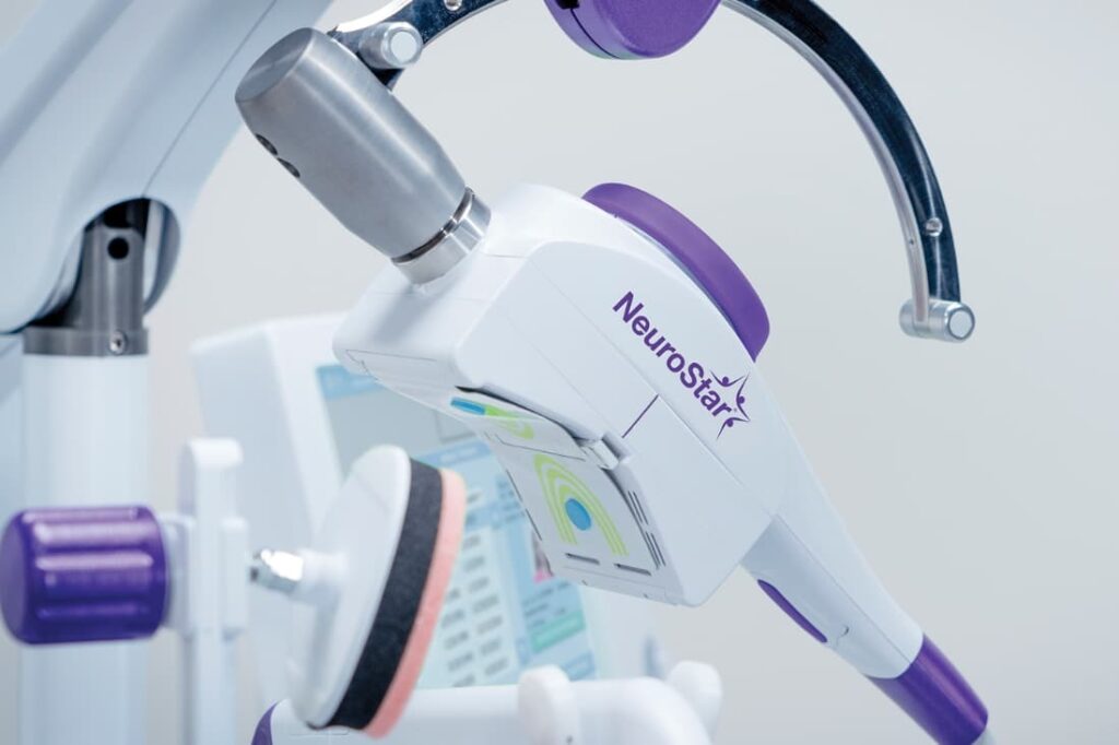 TMS vs Spravato treatment option represented by a close-up of a NeuroStar transcranial magnetic stimulation device. 