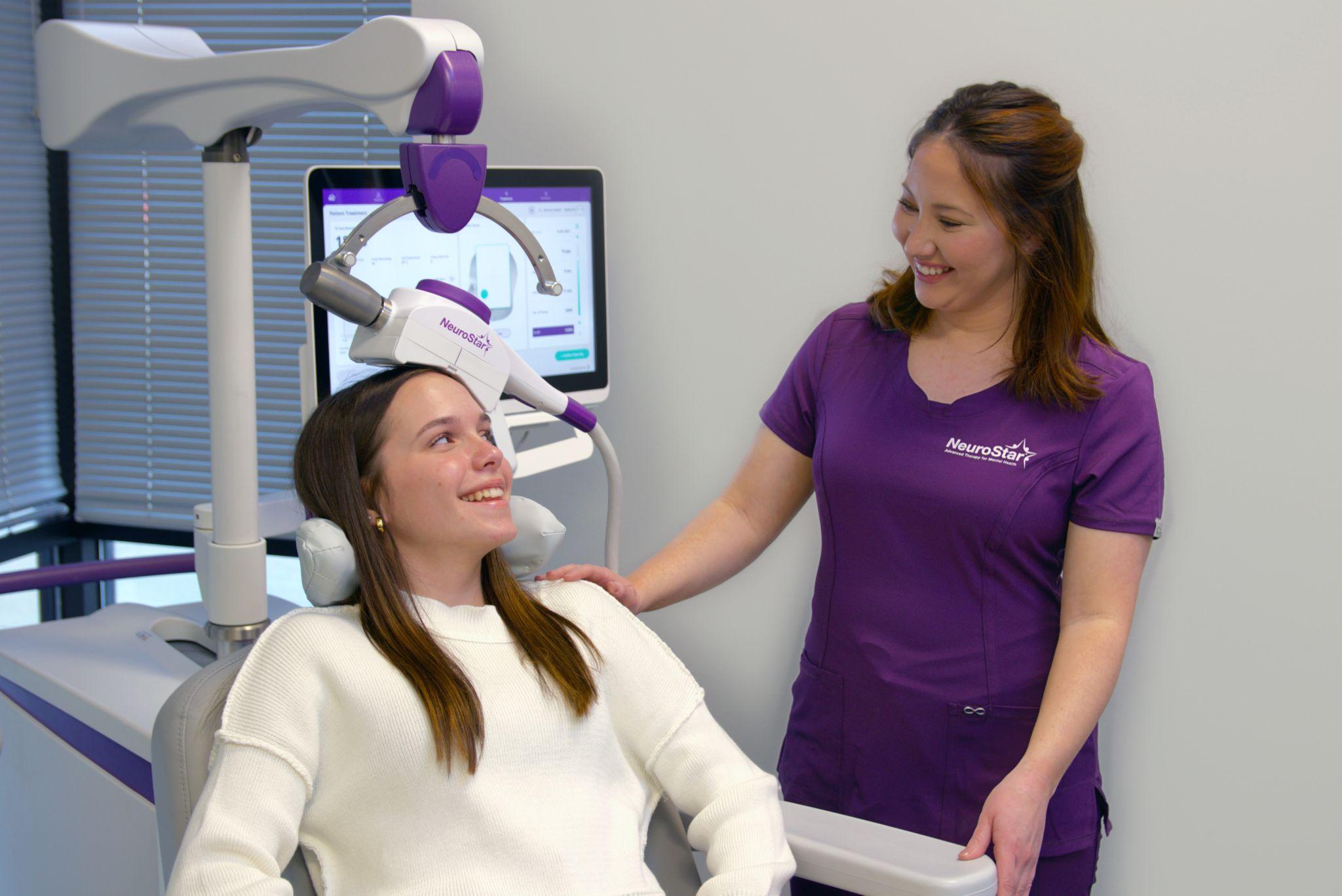 Teen patient smiles while receiving NeuroStar TMS treatment from a medical professional.