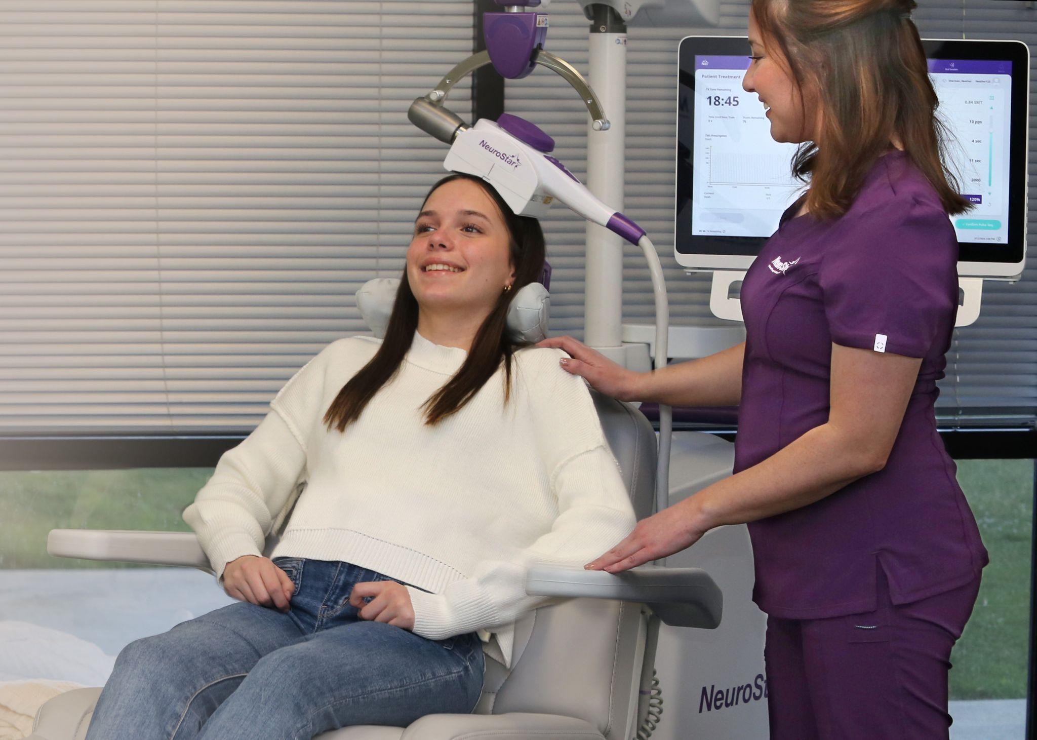 Teenager smiling during a NeuroStar TMS therapy session with a nurse.